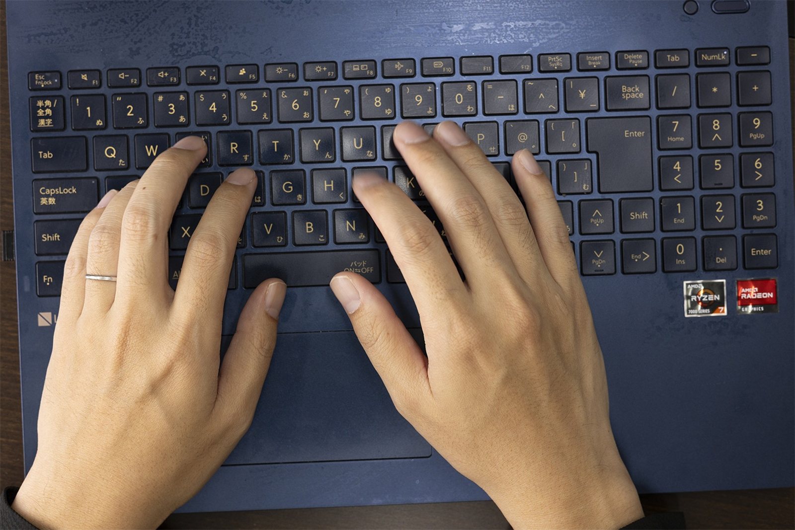 ノートパソコンのキーボードに両手を置いた手元